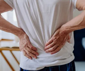 Elderly person holding lower back showing signs of discomfort