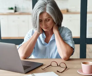 Woman rubbing her neck at a desk showing muscle tension